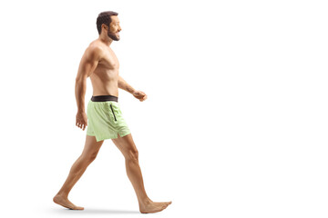Full length profile shot of a man in swimming shorts walking