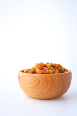 Golden dried raisins in wooden bowl isolated on white background