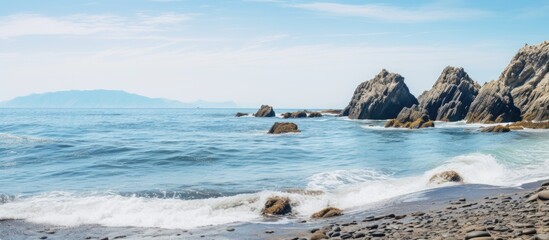 Rocky shoreline with waves crashing against the beach and a majestic mountain in the far distance. with copy space image. Place for adding text or design