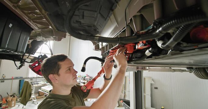 A mechanic is installing and connecting an electric motor to a vehicle in a workshop, focusing on EV maintenance and repair. EV repair concept. Auto Service, Electric Car Battery Handling.