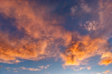 Morgen- oder Abendhimmel mit aufgelockerter, vom Wind verwirbelter, orangefarbener Bewölkung, bei klarer Luft und blauem Himmel