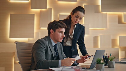 Worried colleagues discussing papers looking computer screen at office closeup