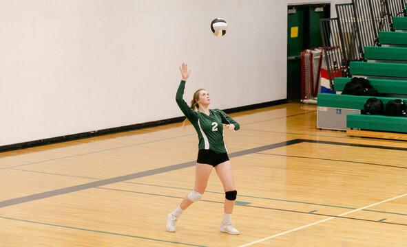 A High School Athlete Serves a Volleyball - Powered by Adobe