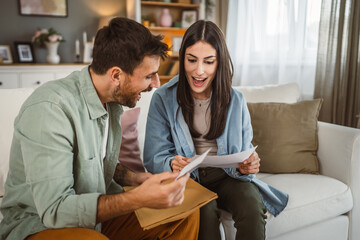 Couple boyfriend and girlfriend open letter envelope together at home