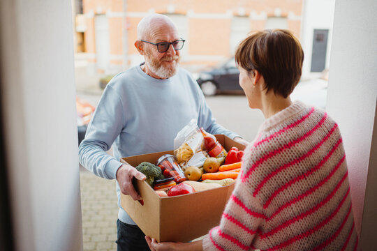 Man delivering grocery box to woman at door