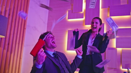 Overjoyed winners throwing dollars in neon cabinet closeup. Rejoicing partners