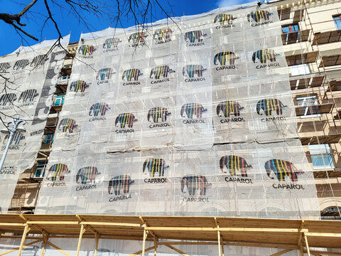 Minsk, Belarus. Mar 16, 2024. Scaffolding and Caparol mesh on heritage building for renovation project, reconstruction work. Historical building with scaffolding and protective mesh.