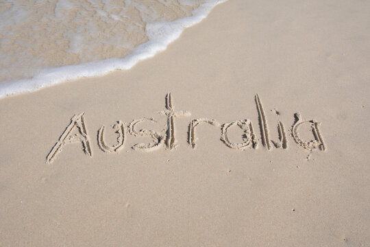 Australia written on a beach. Wave in top corner with copy space.
