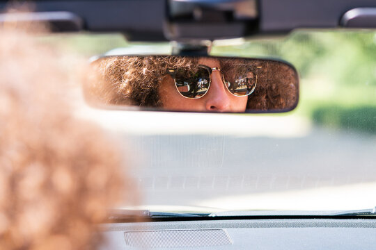 Young woman reflected in her car's rearview mirror