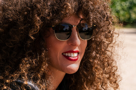 Curly haired young woman with sunglasses and red lips