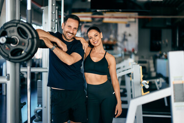 Portrait of a fitness couple, posing for the camera, leaning on the squat rack.