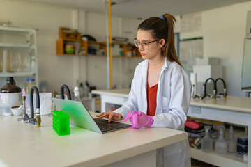 Concentrated female scientist making research with laptop in lab