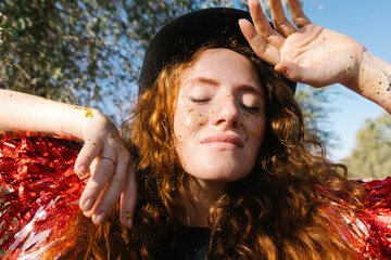 A woman with gold sparkles on her face outdoors