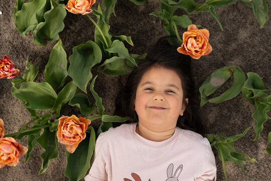 Smiling girl lying on bicolor tulip field