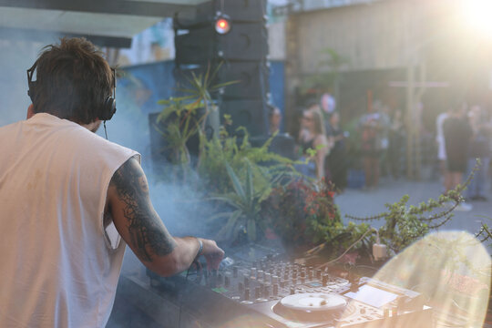 View from behind DJ: people dancing at dawn at tropical party