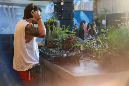 Tropical DJ touching his headphones while playing on table with plants