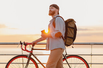 handsome bearded man traveling with bicycle in morning sunrise by the sea