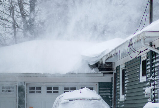 Snow blowing off the roof of a residential house during a blizzard