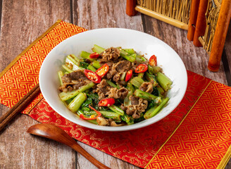 Shacha beef with vegetables, chopsticks and spoon served in dish isolated on napkin side view on wooden table of taiwanese food