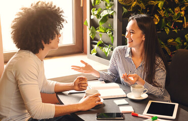 Informal job interview. Cheerful woman talking with new candidate in cafe, free space