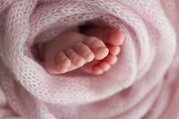 Close-up of tiny, cute, bare toes, heels and feet of a newborn girl, boy. Baby foot on pink soft...