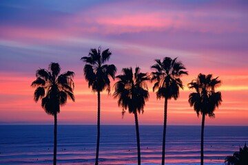 Obraz premium Vibrant tropical sunset silhouettes of palm trees on a coastal beach with a tranquil ocean view at dusk. Creating a peaceful and serene landscape with warm. Colorful evening colors. Perfect for travel