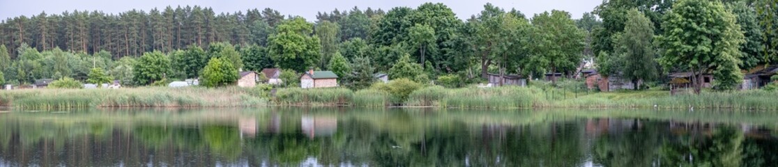 Fototapeta premium old poor village houses on lake side. Panorama landscape