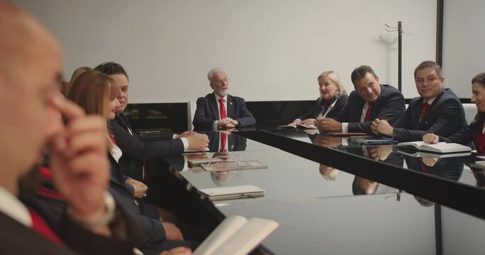 Large group of professors discussing curriculum plans for the new year of studying, formally dressed in the meeting room