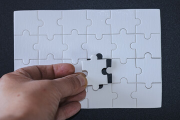 Person holding the last piece of puzzle and is about to finish it