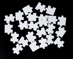 Disassembled white puzzle, on a black background, ready to be solved