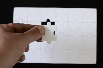 Person holding a puzzle piece, about to place the last piece