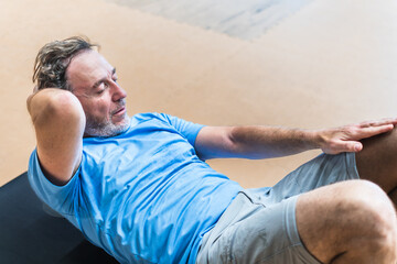 Close up of a senior man is doing sit ups on a mat