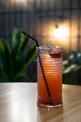 Glass with fresh strawberry cocktail and straw on table in cafe