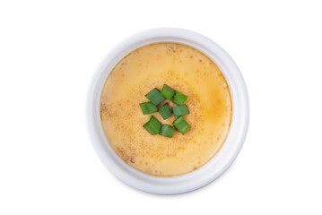 Asian steamed eggs in a bowl with soy sauce and scallions on a white isolated background