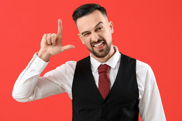 Handsome man showing loser gesture on red background