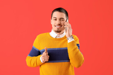 Cool young man talking by phone on red background
