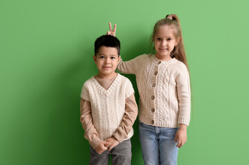 Cute little children in knitted sweaters on green background