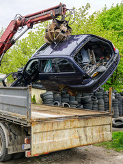 The process of loading an abandoned car wreck using a hydraulic loader mounted on a tow truck