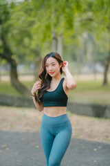 Asian woman trainer is engaged in fitness in public park. Sporty woman does exercises in the open air. Healthy lifestyle, sports outdoor activities in park