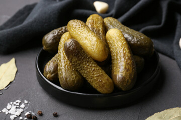 Plate with pickled cucumbers on black background