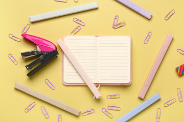 Blank notebook with school stationery on color background