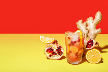 Glass of tasty pomegranate cocktail with lemon and ginger root on color background