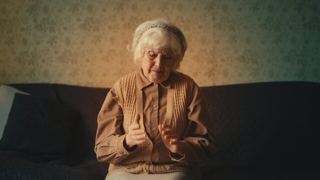 Desperate senior woman crying while sitting on sofa, poverty and poor health