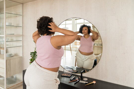 Woman Styling Hair in Mirror