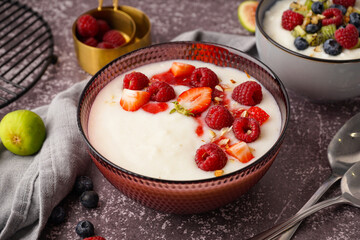 Bowl of tasty semolina porridge with fresh berries on grey background