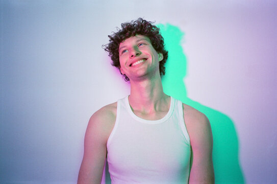 Cheerful young man with happy smile in neon studio