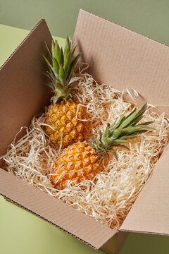 Open cardboard box with two sweet exotic pineapples inside