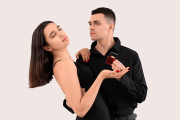 Elegant young couple with perfume on light background