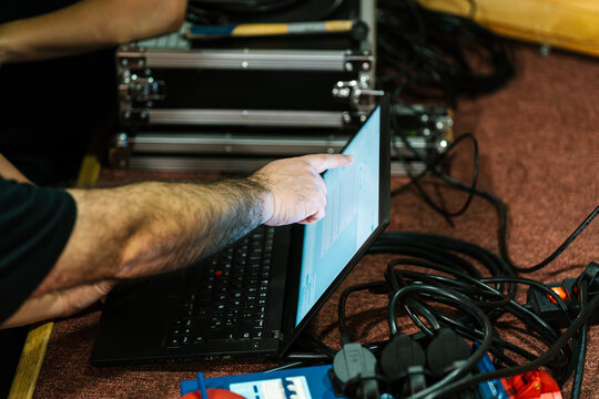 Sound engineer pointing at netbook screen in backstage