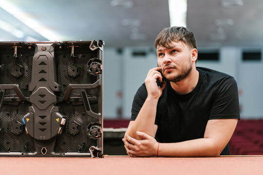 Serious technician on phone call while working to mount video wall